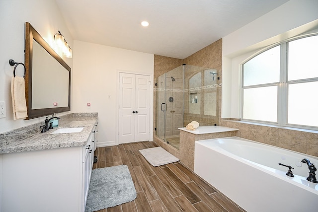 bathroom featuring vanity, a garden tub, wood tiled floor, recessed lighting, and a shower stall