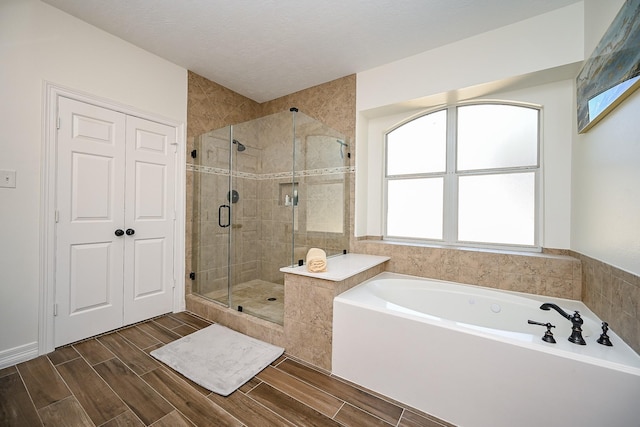 bathroom with wood finish floors, a garden tub, and a stall shower