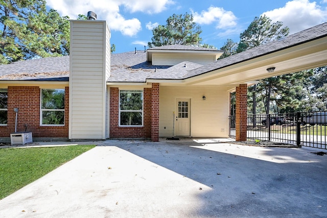 back of house featuring brick siding, a patio, fence, and a chimney
