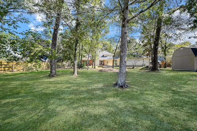 view of yard featuring a storage shed, fence, and an outdoor structure
