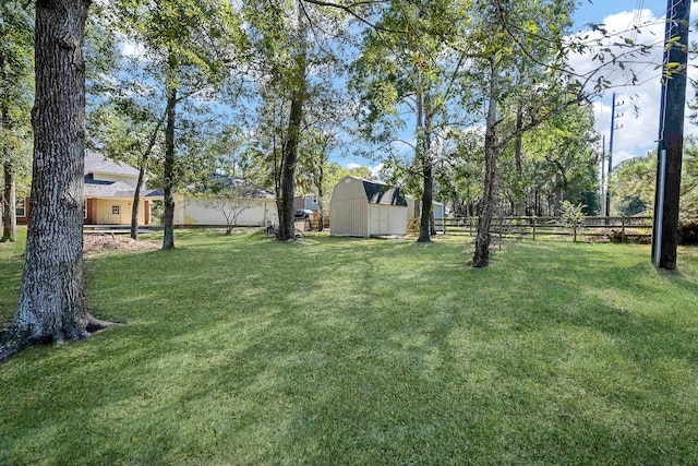 view of yard with an outdoor structure, fence, and a shed