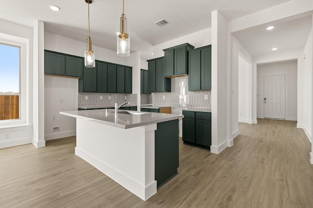2219 Inglenook Grove Dr, Katy, TX 77493 - kitchen featuring a sink, green cabinets, backsplash, an island with sink, and light wood-style floors