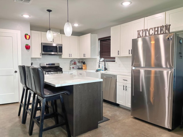kitchen featuring a kitchen island, a sink, white cabinets, concrete floors, and stainless steel appliances