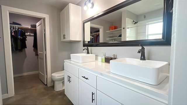 bathroom with a sink, walk in shower, toilet, and concrete floors