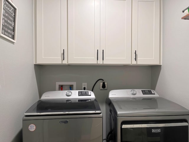 clothes washing area featuring washer and clothes dryer and cabinet space
