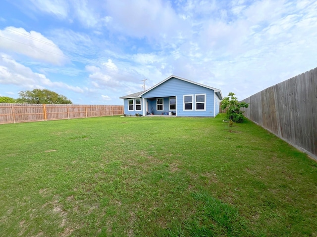 back of property featuring a fenced backyard and a yard