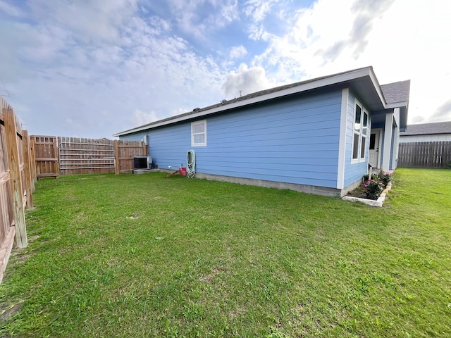 rear view of house with a lawn, a fenced backyard, and central AC unit