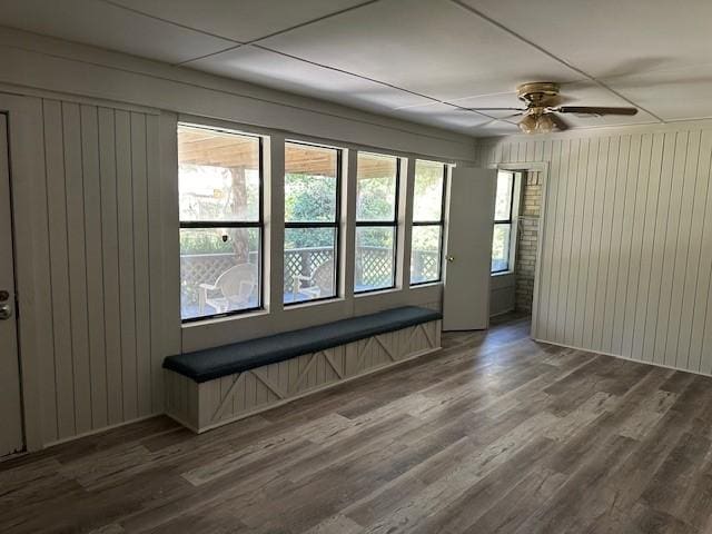 unfurnished room featuring wooden walls, ceiling fan, and wood finished floors
