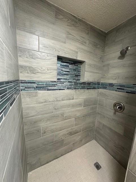 full bathroom featuring a textured ceiling and a tile shower