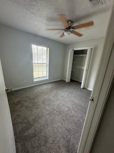 unfurnished bedroom featuring ceiling fan, a textured ceiling, visible vents, baseboards, and carpet