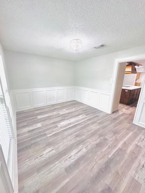 unfurnished room with wainscoting, a wealth of natural light, and a decorative wall