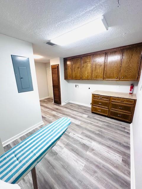 interior space with light wood-type flooring, a textured ceiling, and visible vents