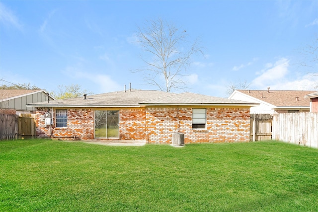 rear view of house with a lawn, fence, and cooling unit