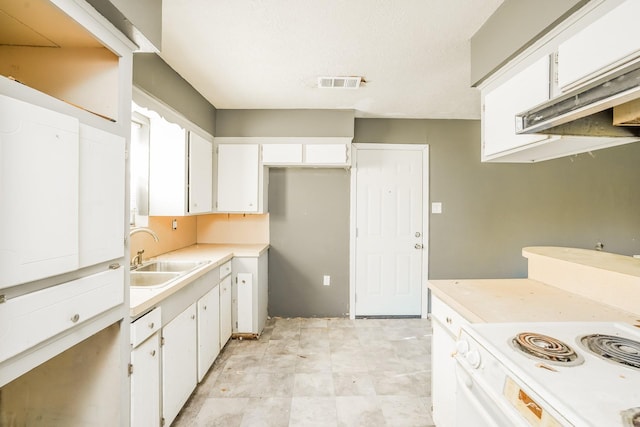 kitchen featuring light countertops, white cabinetry, visible vents, and a sink