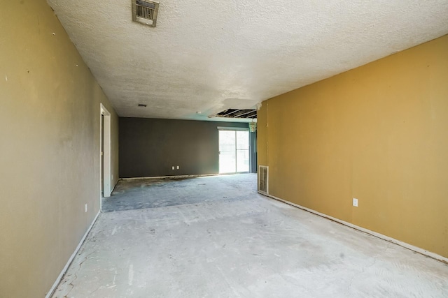 unfurnished room with baseboards, a textured ceiling, and visible vents