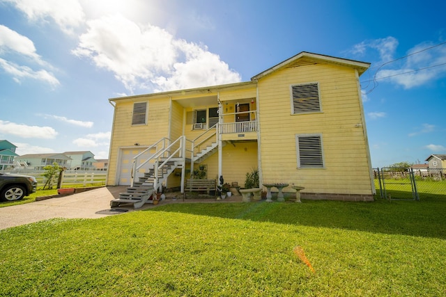 rear view of property with a garage, fence, concrete driveway, a yard, and stairway