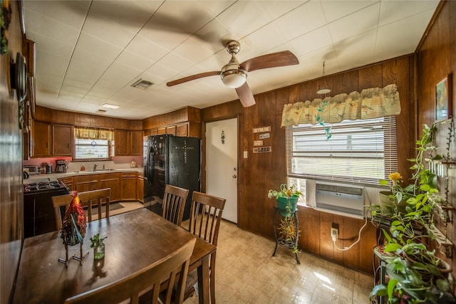 kitchen with visible vents, freestanding refrigerator, wood walls, light floors, and ceiling fan