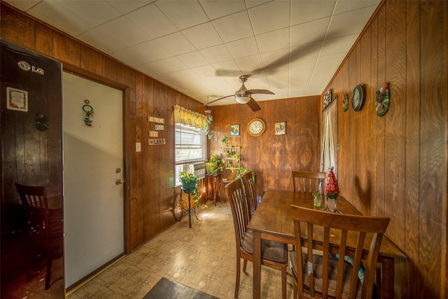 dining area with wooden walls, tile patterned floors, and a ceiling fan