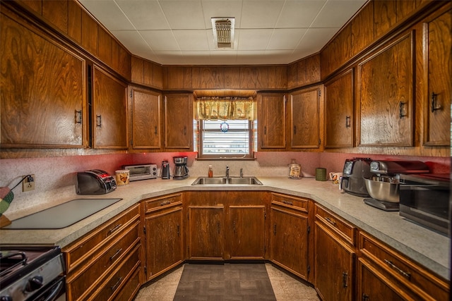 kitchen with a sink, stainless steel gas stove, light countertops, tile patterned floors, and visible vents