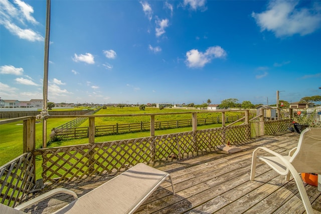wooden terrace with a lawn, fence, and a rural view