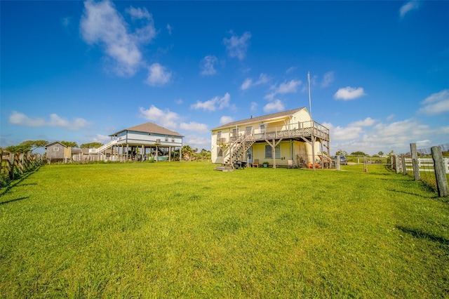 back of property featuring a lawn, a wooden deck, stairway, and fence