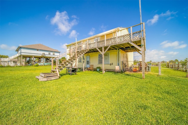 rear view of house featuring a lawn, stairway, fence, and a deck