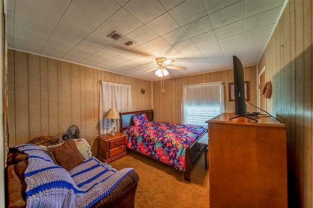 bedroom featuring wooden walls, ceiling fan, carpet flooring, and visible vents