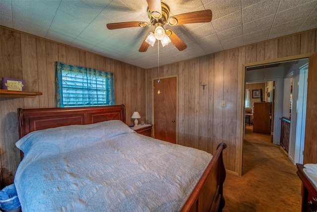 bedroom featuring wooden walls, carpet floors, and a ceiling fan