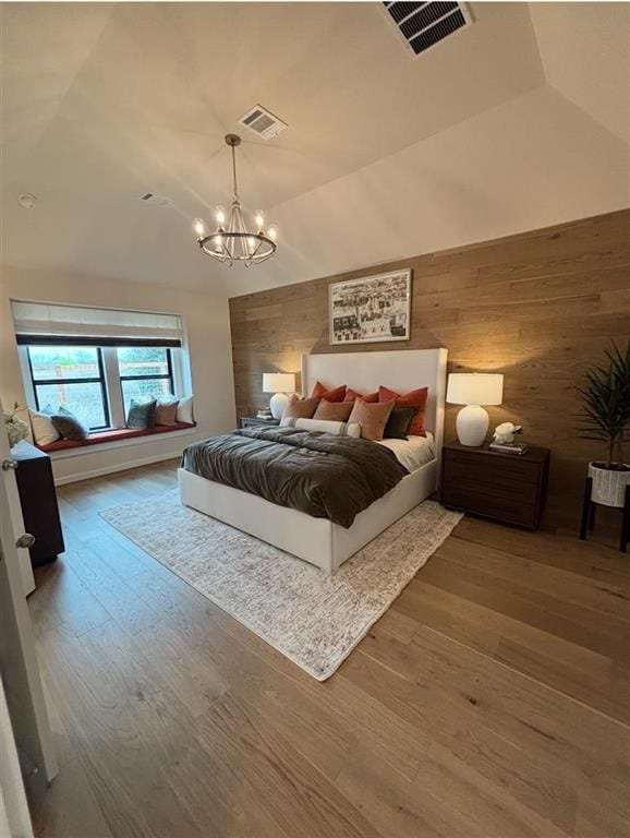 bedroom featuring wooden walls, visible vents, an inviting chandelier, and vaulted ceiling