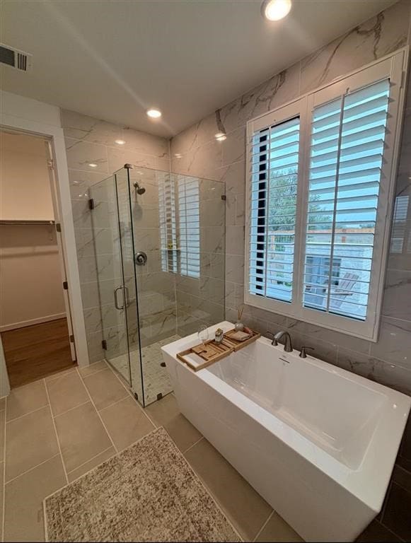 full bathroom featuring visible vents, a freestanding bath, tile walls, a stall shower, and tile patterned floors
