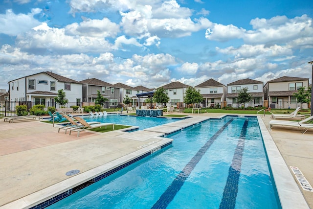 community pool featuring a patio, fence, and a residential view