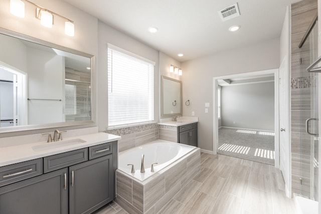 bathroom featuring visible vents, a sink, a bath, and a stall shower