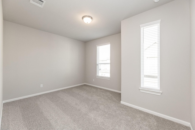 empty room with light colored carpet, baseboards, and visible vents