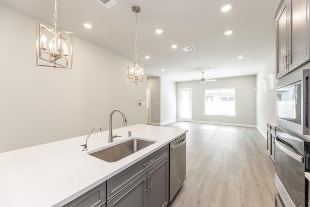 kitchen with a sink, appliances with stainless steel finishes, gray cabinets, and light countertops