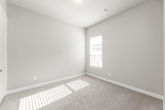empty room with baseboards, light carpet, and visible vents