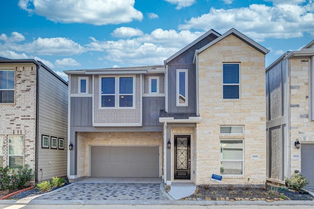 view of front of property featuring board and batten siding, an attached garage, and stone siding