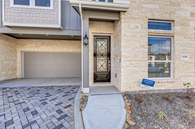 entrance to property featuring an attached garage and stone siding