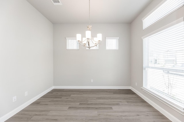 unfurnished dining area with a chandelier, plenty of natural light, visible vents, and light wood-style floors