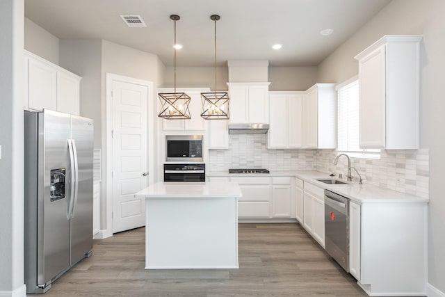 3011 Valley Peak Dr, Houston, TX 77063 - kitchen featuring visible vents, a kitchen island, under cabinet range hood, a sink, and black appliances