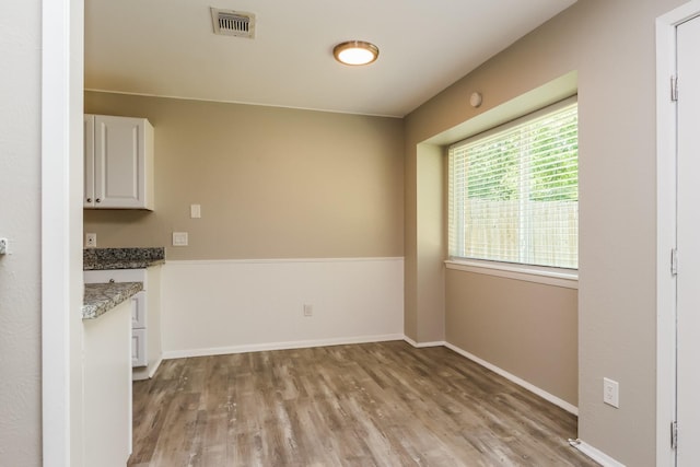 unfurnished dining area with baseboards, visible vents, and light wood-style flooring