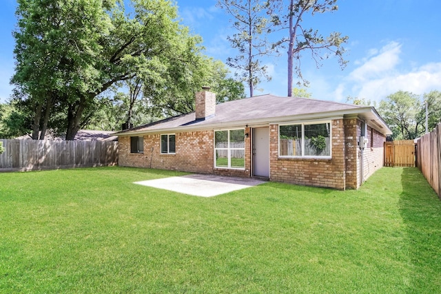 back of property featuring a patio, a fenced backyard, a chimney, brick siding, and a lawn