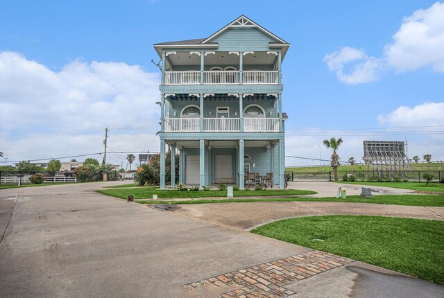 view of front of home featuring fence, concrete driveway, a front lawn, and a balcony