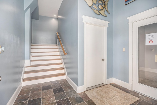 stairway featuring baseboards, stone tile floors, and recessed lighting