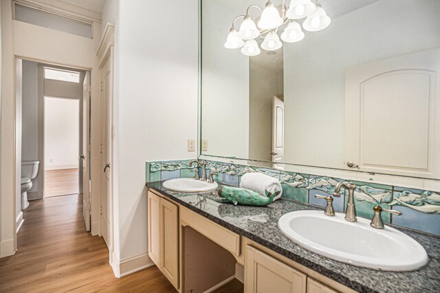 bathroom with a sink, double vanity, toilet, and wood finished floors