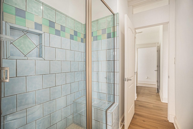 bathroom with baseboards, a stall shower, and wood finished floors
