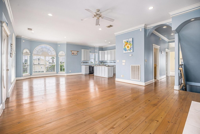 unfurnished living room featuring visible vents, ornamental molding, ceiling fan, and light wood-type flooring