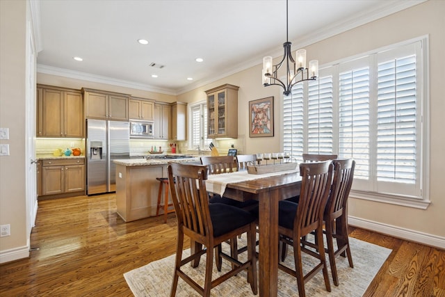 dining area featuring visible vents, baseboards, a notable chandelier, ornamental molding, and light wood-style flooring