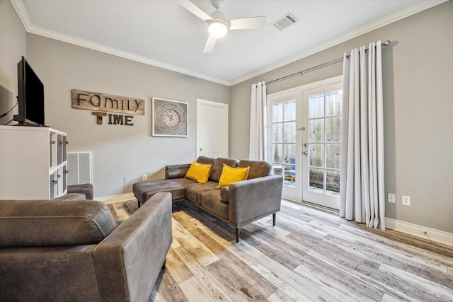 living room featuring crown molding, a ceiling fan, visible vents, and light wood finished floors