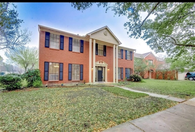 greek revival house featuring brick siding and a front yard