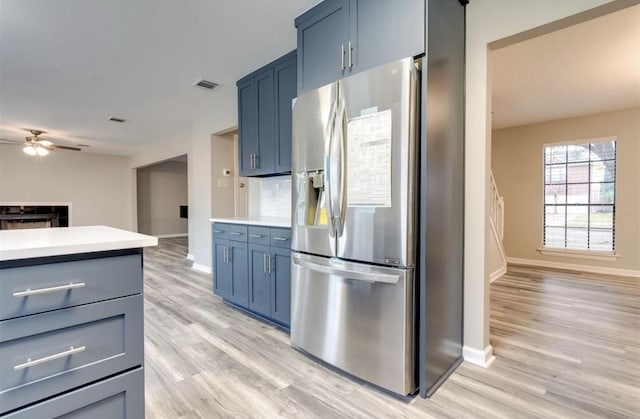 kitchen featuring ceiling fan, visible vents, light wood-type flooring, baseboards, and stainless steel fridge